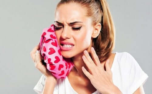 A woman in pain with an ice compress that provides toothache relief.
