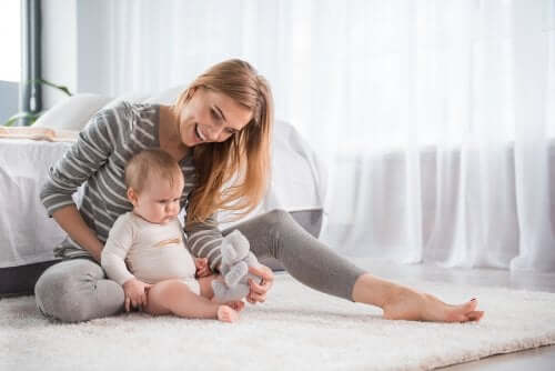 A woman sitting on the floor with a baby.