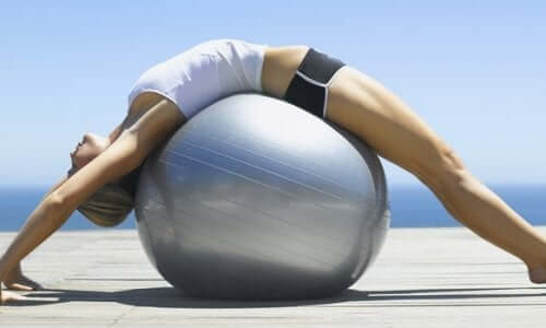 A woman stretching over a yoga ball.