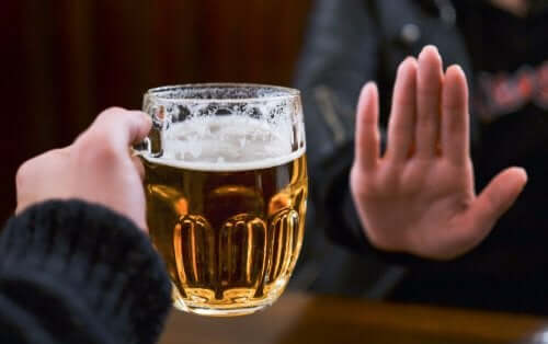 Person siger nej til øl, da alkohol er almene fjender af sund hud