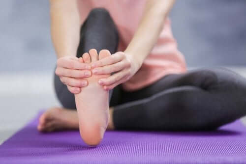A woman giving herself a foot massage.