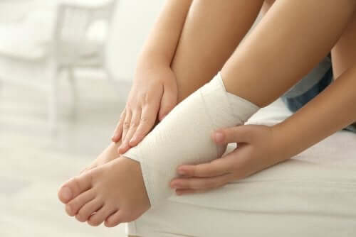 A woman looking at her bandaged foot.
