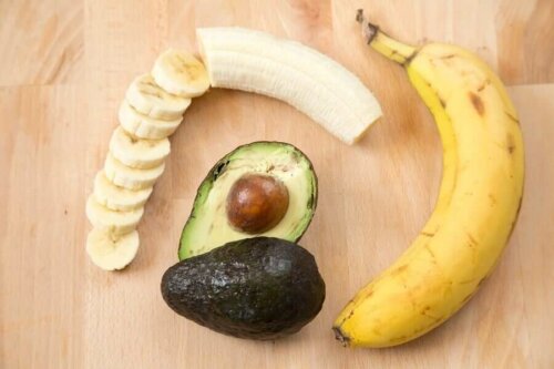 Some sliced banana and avocado on a wooden table.
