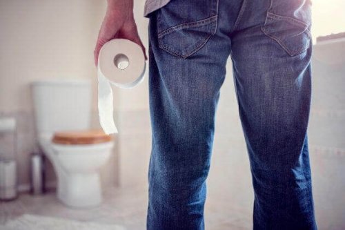 Man standing in bathroom with toilet paper and constipation benefits of castor oil