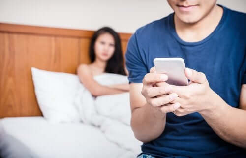 A jealous woman looking at her partner while he's texting someone.