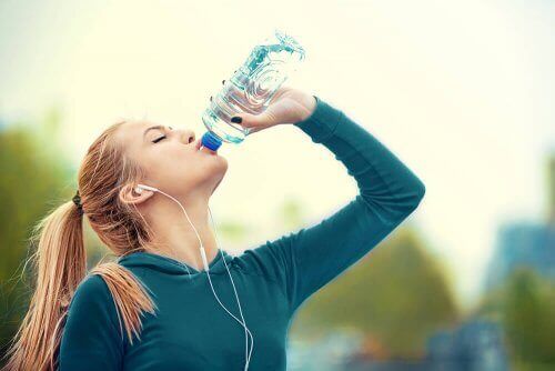Жена, тичаща навън, пиеща от бутилка вода.