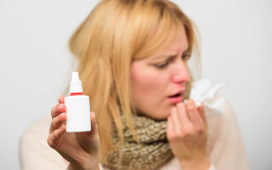 A woman taking nasal spray for her cold.