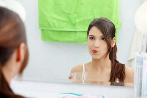 A woman using mouthwash.