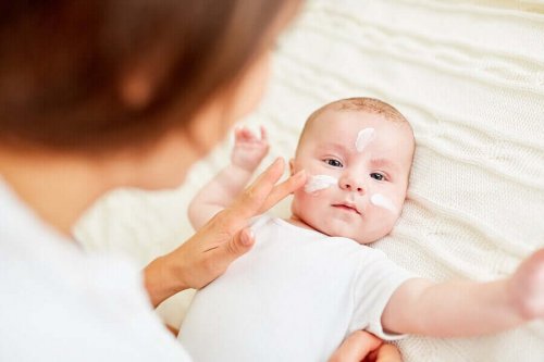 A woman putting lotion on a baby's face.