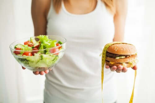 A woman with a salad and a hamburger.