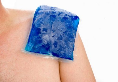 A person applying a cold compress on their shoulder.