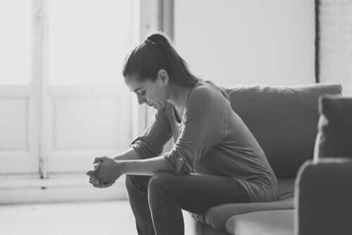 A sad woman sitting on a couch.