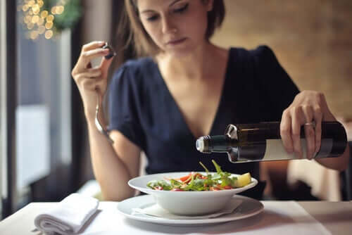 A woman adding olive oil to a salad.