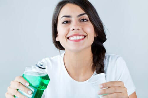 A woman pouring mouthwash in a cup.