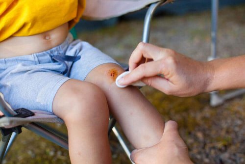 A person cleaning a child's wound.