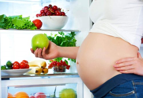 A pregnant woman holding an apple.