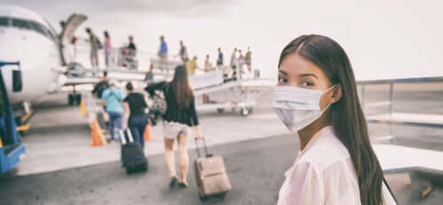 A woman wearing a face mask to go on a plane.