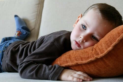 A boy laying on the couch watching television.
