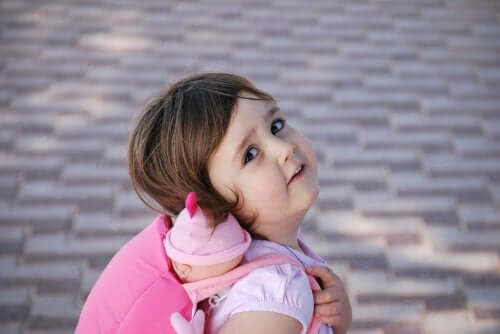 A girl carrying her doll on her back.
