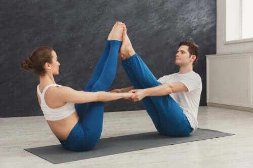 A couple doing the boat pose (Navasana).