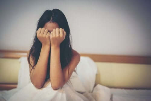 A woman covering her face with her hands, protecting herself from abuse.