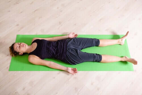A woman lying on a yoga mat.