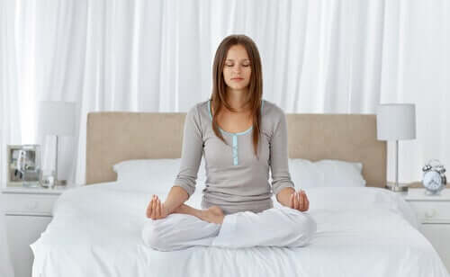 A woman meditating in bed.