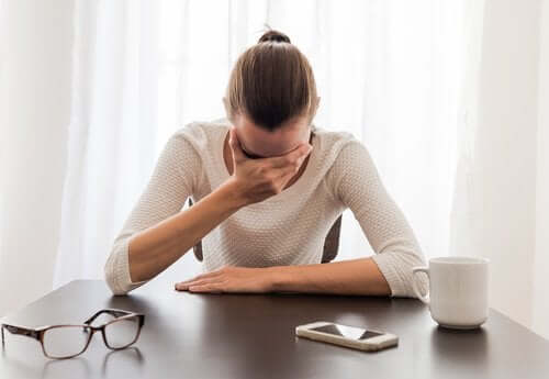 Woman having anxiety attack with head in hand at a table.