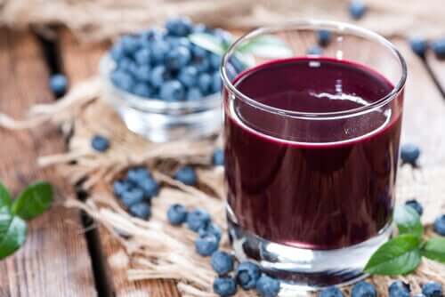 Glass of blueberry sauce with blueberries in the background.
