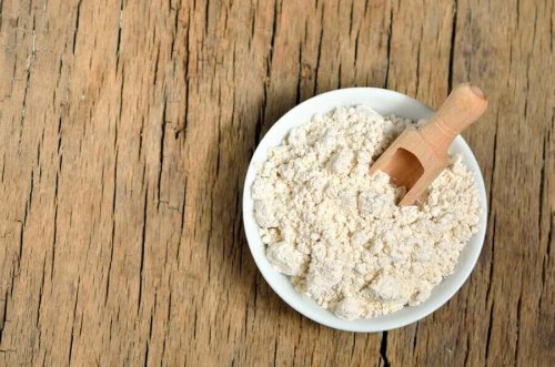 Lumpy powder in a bowl with a wooden scoop.