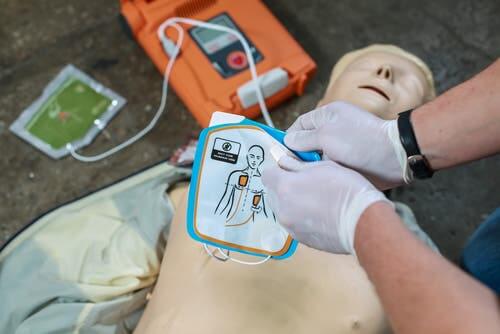Using defibrillator on practice dummy for cardiopulmonary arrest.