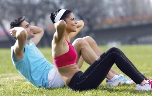 People doing sit ups on the grass.