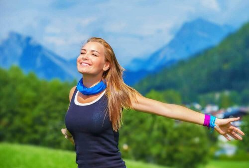 Woman outside practicing earthing and smiling at sun.