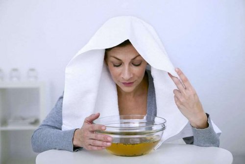 Woman with towel on her head breathing eucalyptus vapors from a bowl.