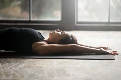 Woman laying on her back on a yoga mat.