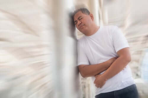 A man leaning on a wall and holding his side from a side cramp.