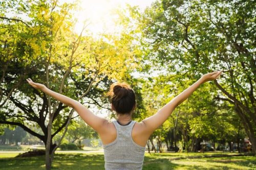 Woman with arms raised in a park.
