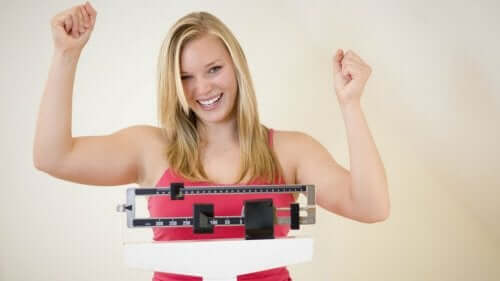 Woman standing on scale smiling.