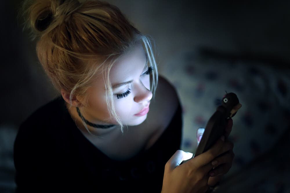 A woman texting in the dark.