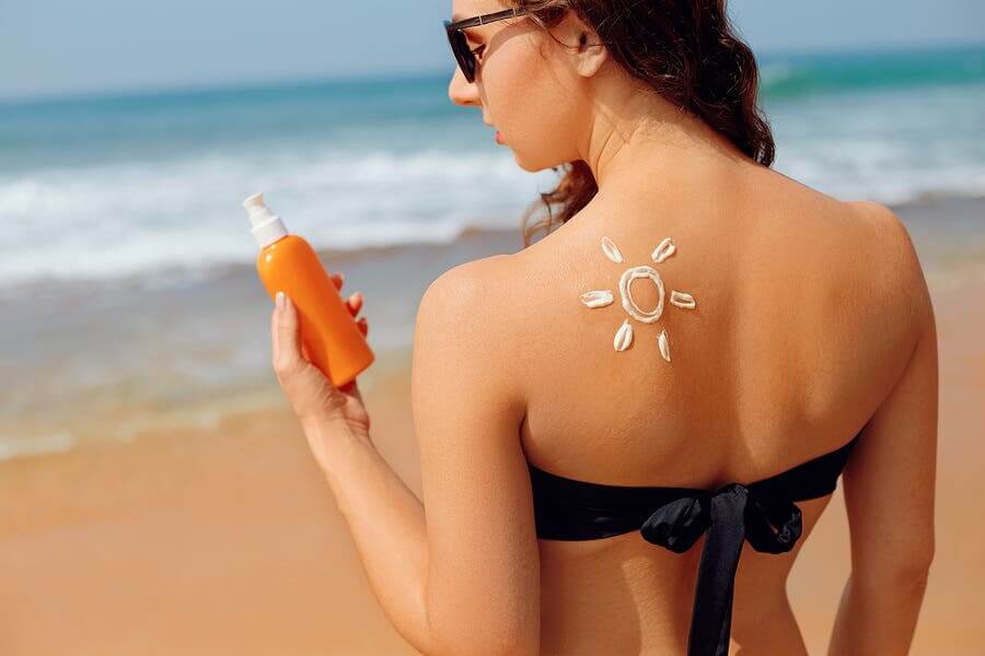 A girl applying sunscreen outside.