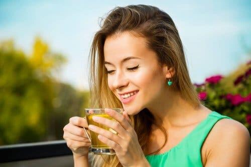 A woman smiling drinking tea.