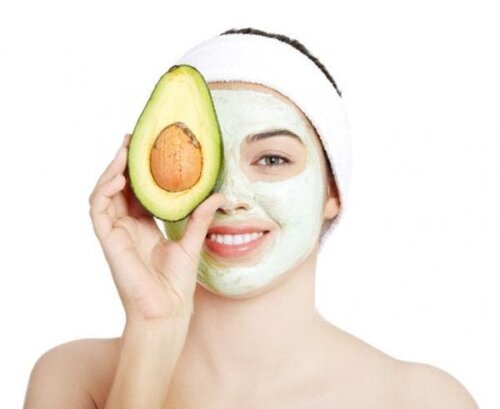 Woman holding an avocado with a mask on to reduce the appearance of wrinkles