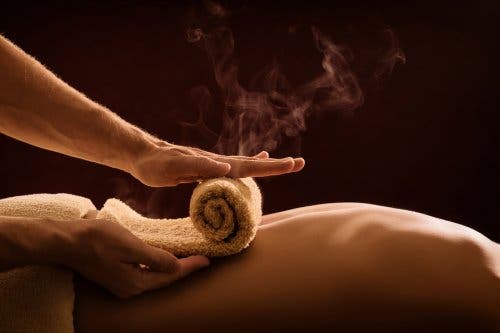 Rolling a hot towel on a person's back.
