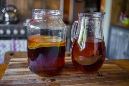 A large jar and pitcher of kombucha tea next to each other.