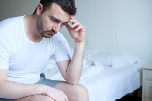 Man sitting on side of bed, upset about premature ejaculation.