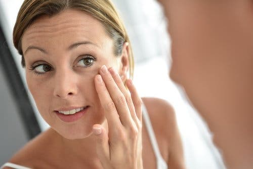 Woman looking at her perfect skin in the mirror reduce the appearance of wrinkles
