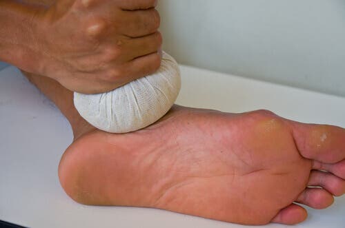 A person applying a cold compress on their foot.
