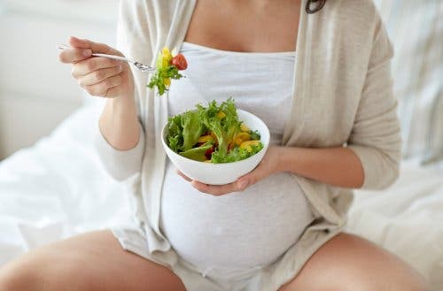A pregnant woman eating a salad.