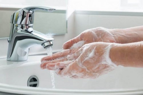 Soapy hands under running water from a tap.