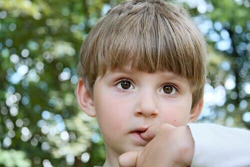A boy biting his nails.